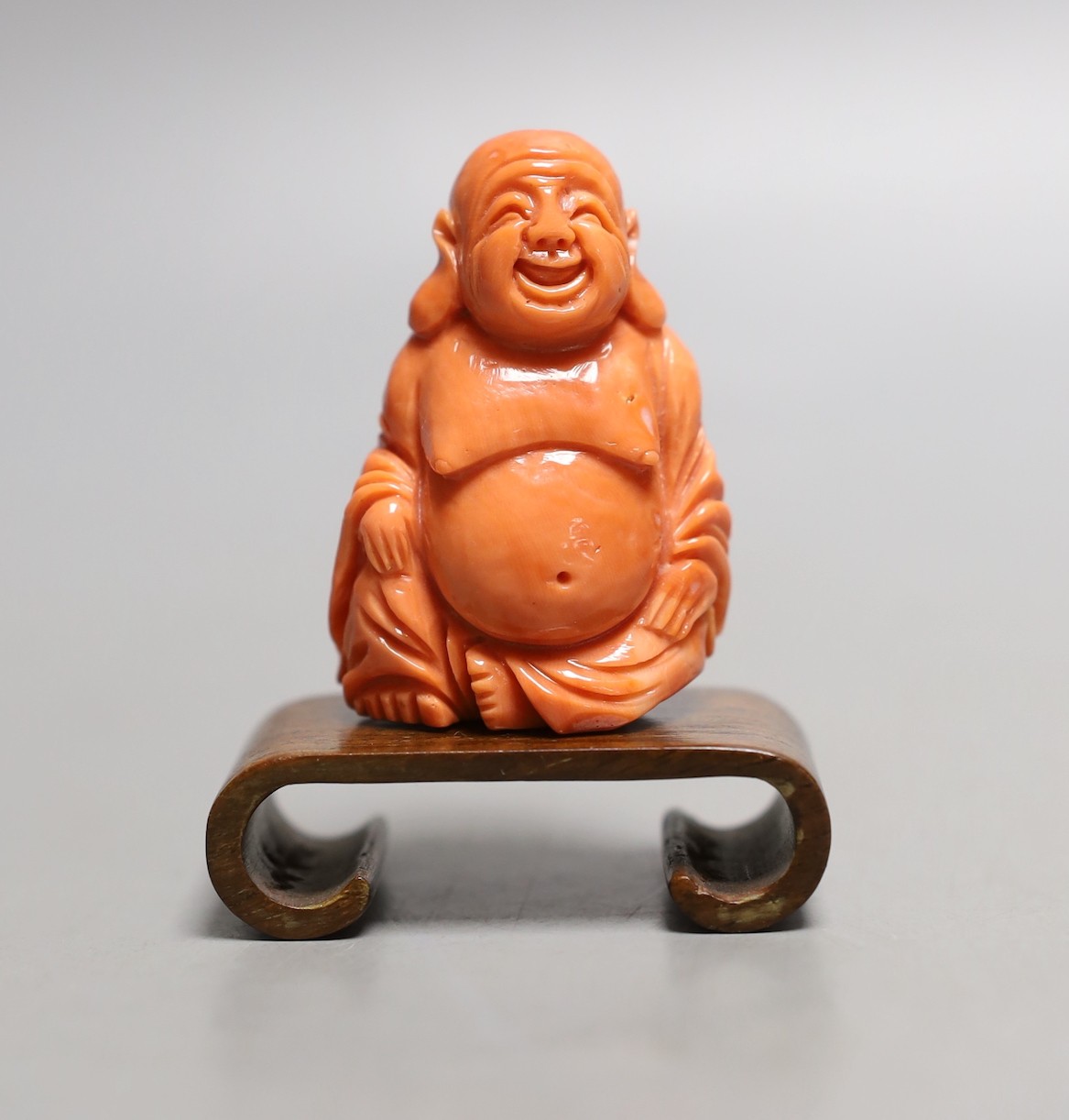 A Chinese carved coral figure of Budai, 5cm excl wooden stand